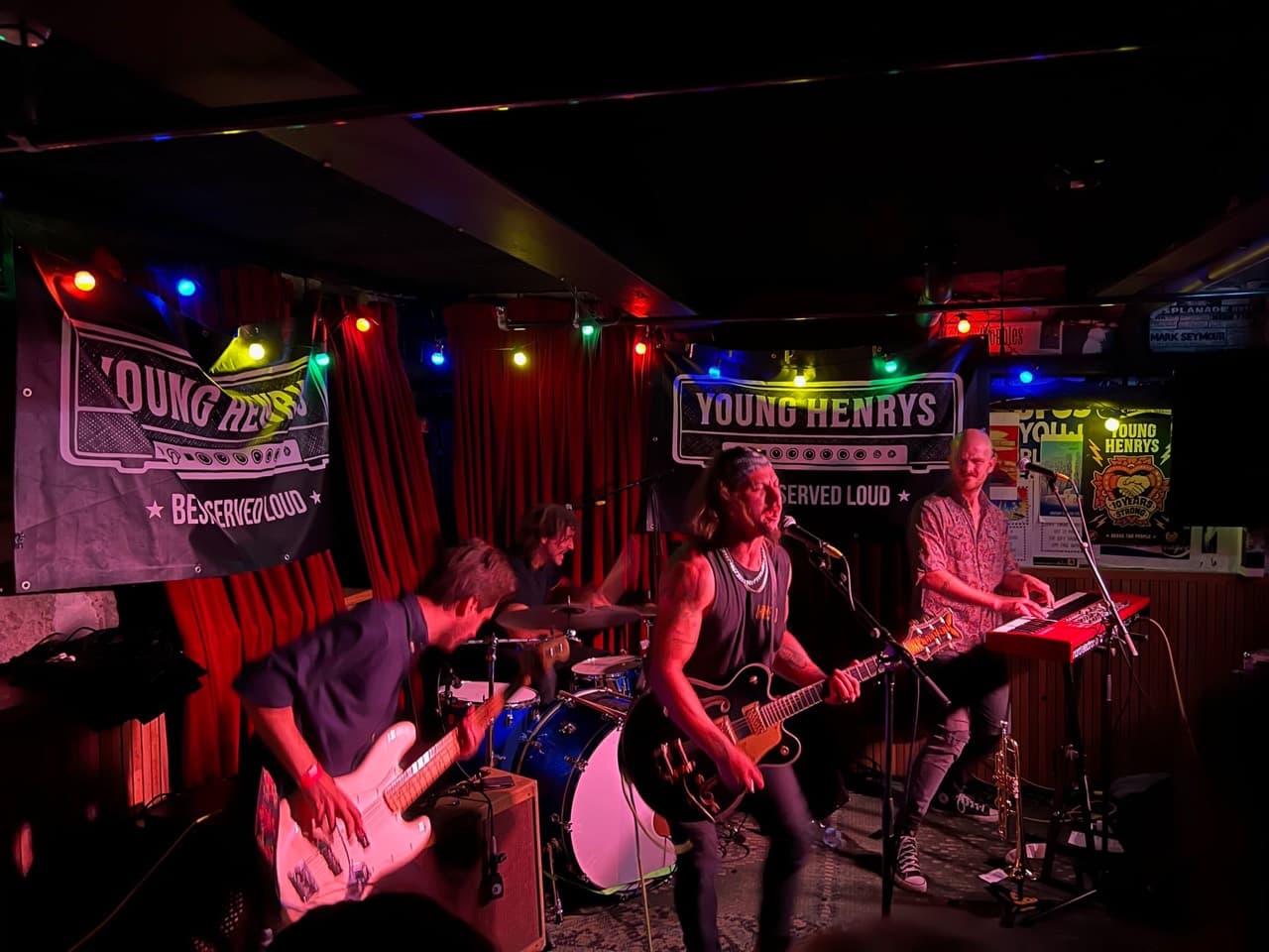 The Dead Amigos performing together in a small venue under red stage lights